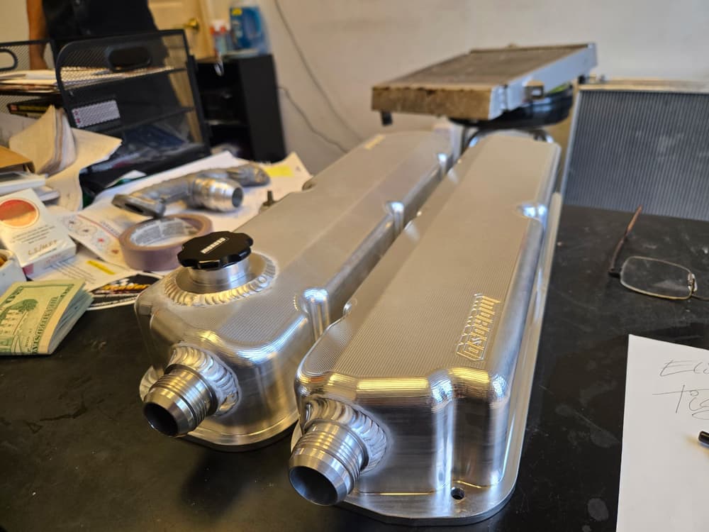 A pair of fabricated billet aluminum valve covers with welded filler neck and AN fittings.